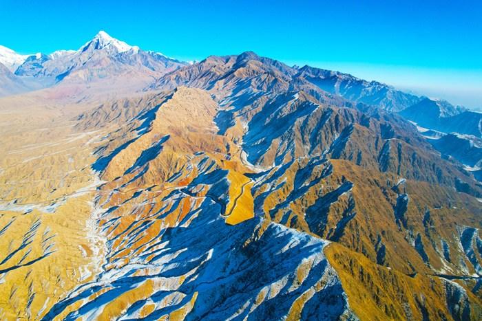 新疆阿克苏山区雪后壮美巍峨 阳光下群山黄白相间